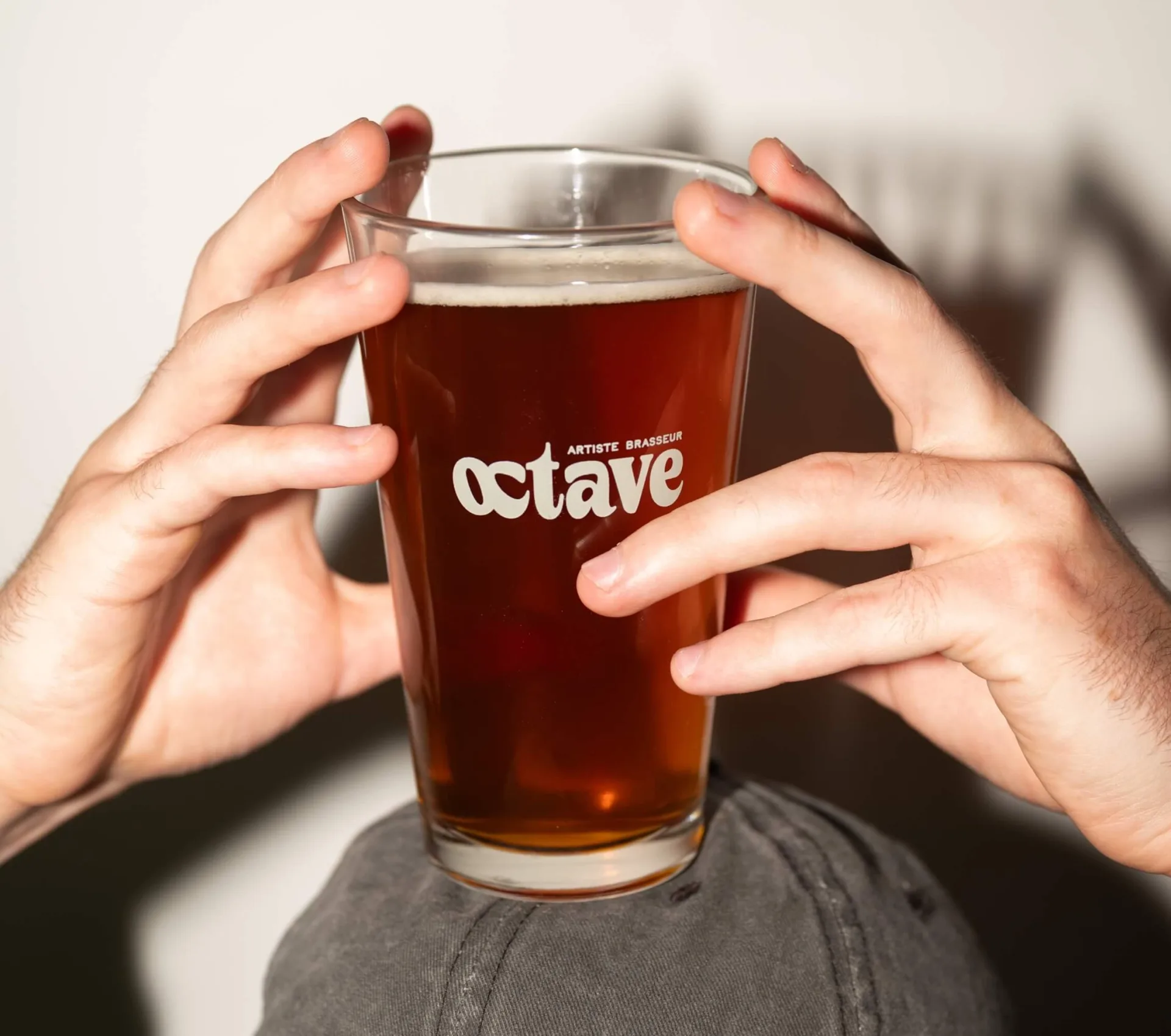 Verre de bière Octave artiste brasseur avec deux mains.